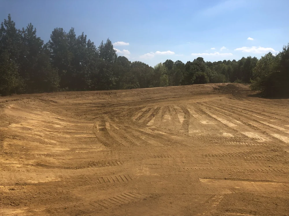 A graded and seeded building pad with fresh contour lines cut into the soil